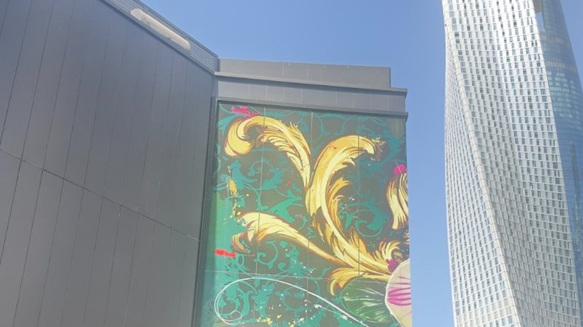 A botanical artwork spanning several printed ACP panels across a building elevation, the panel joins running through the design