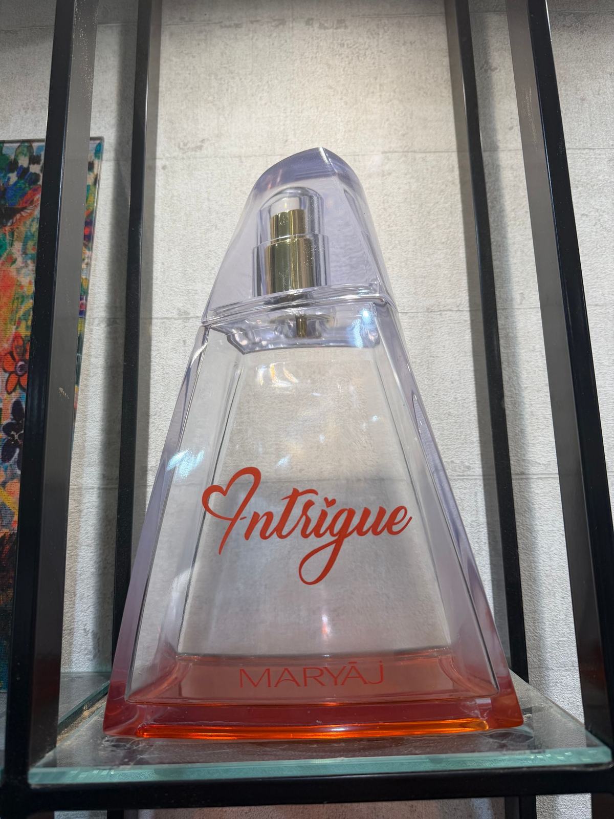 مجسم عملاق شفاف لزجاجة عطر Maryaj Intrigue على شكل هرم، بكتابة حمراء بخط متصل وطوق بلون ذهبي