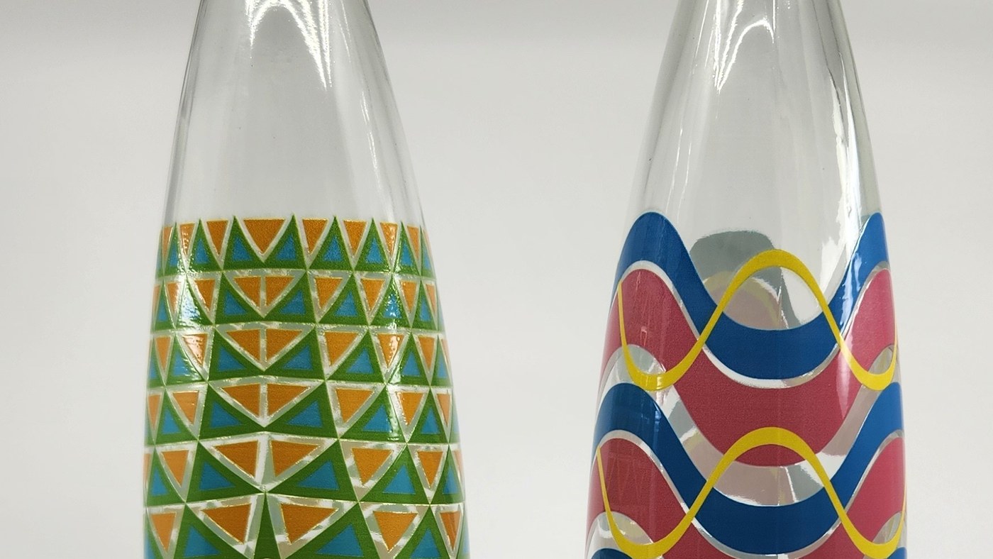 Two clear glass water bottles printed direct with colour patterns, the reverse of the artwork visible through the unprinted glass
