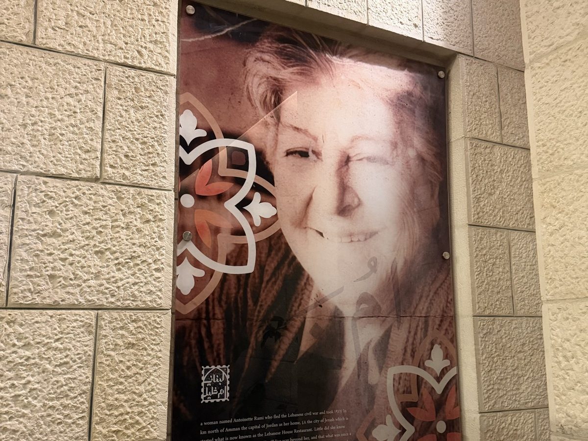 A printed glass heritage panel carrying the story of founder Antoinette Rami, standoff-fixed to limestone
