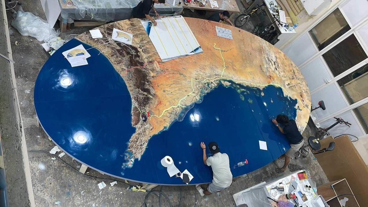 A large oval acrylic panel printed with the terrain of the UAE and the Etihad Rail route, being finished in the model workshop