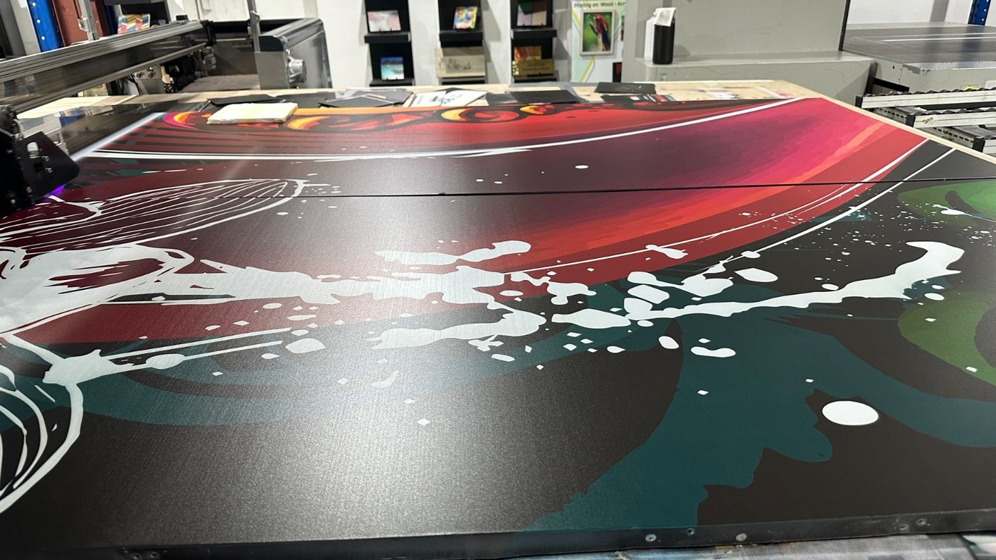 Two ACP panels aligned on the flatbed so the red and white artwork runs unbroken across the join