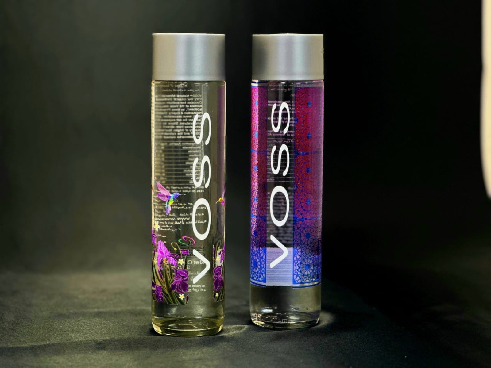 Two glass water bottles printed direct, one with a hummingbird and orchid design and one with a blue geometric pattern