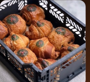 A crate of pain au chocolat, each pastry printed with the same logo in edible ink
