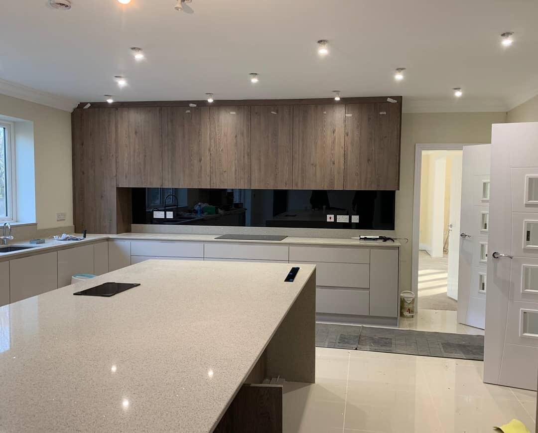 A black reverse printed splashback running the length of a kitchen under timber wall units