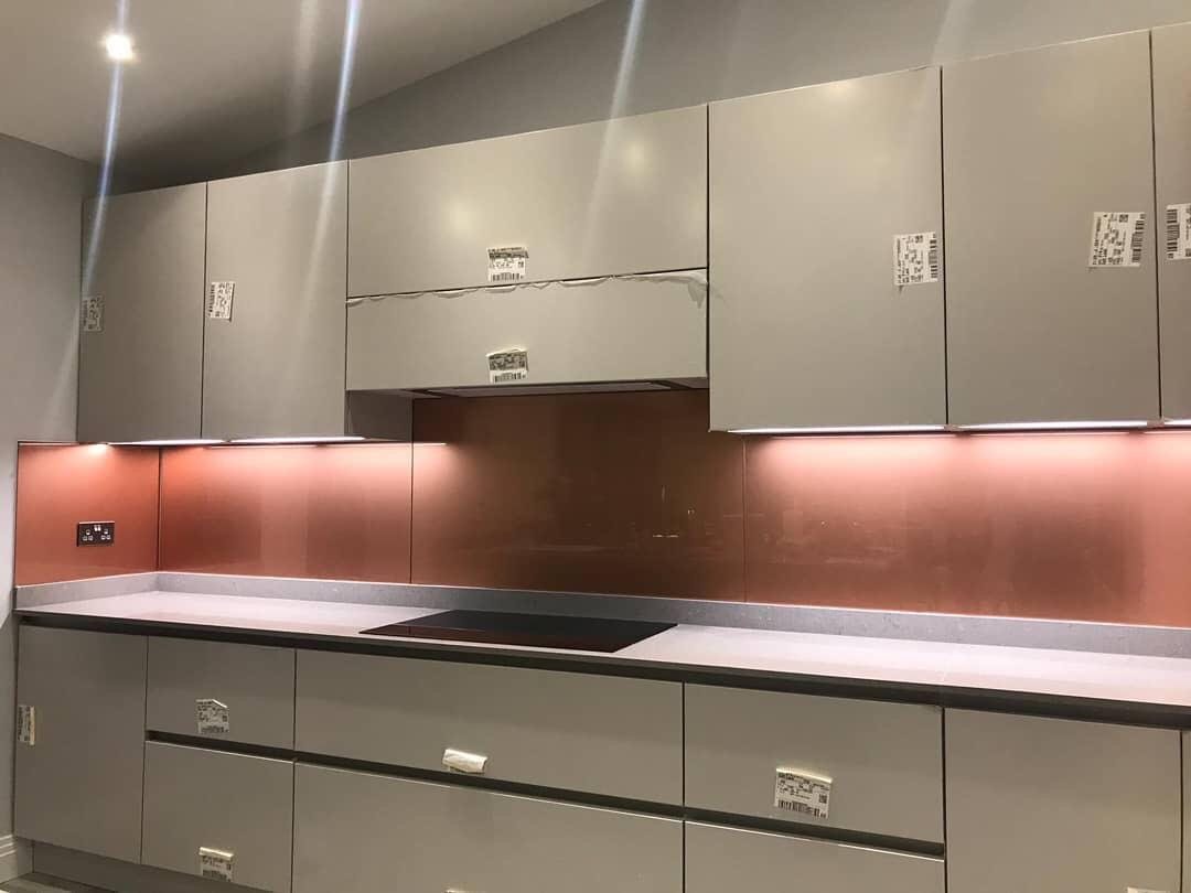 A copper coloured splashback lit by under-cabinet lighting