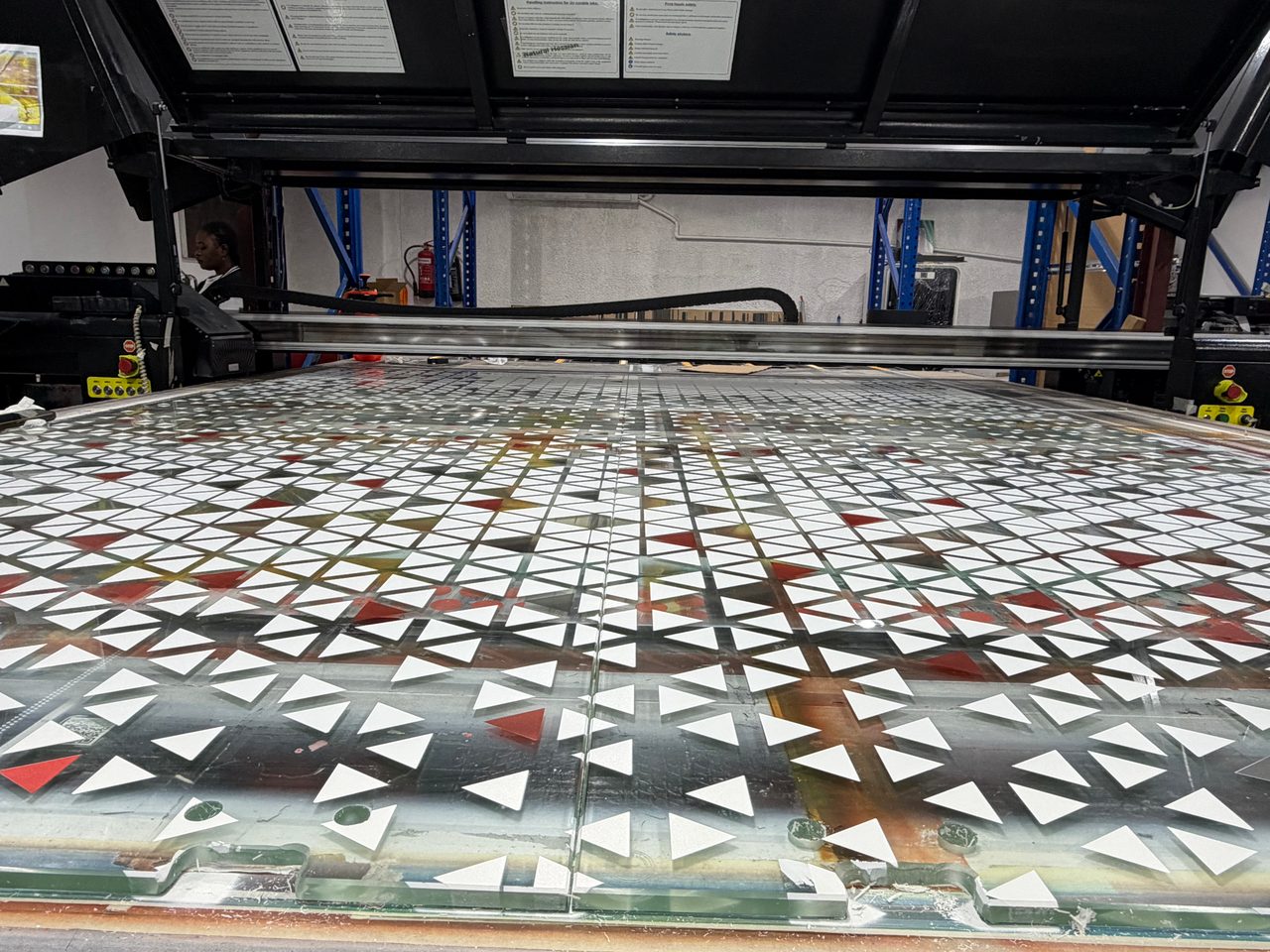 Printed clear glass panels on a flatbed bed, solid white triangles and a few red ones over glass that stays clear between the shapes