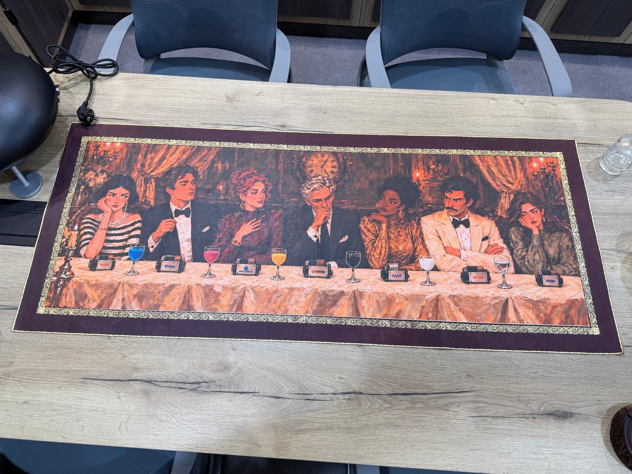 Overhead view of a long natural leather panel on a meeting table, printed in full colour with seven elegantly dressed diners behind printheads and glasses of coloured ink, inside a gold-coloured border