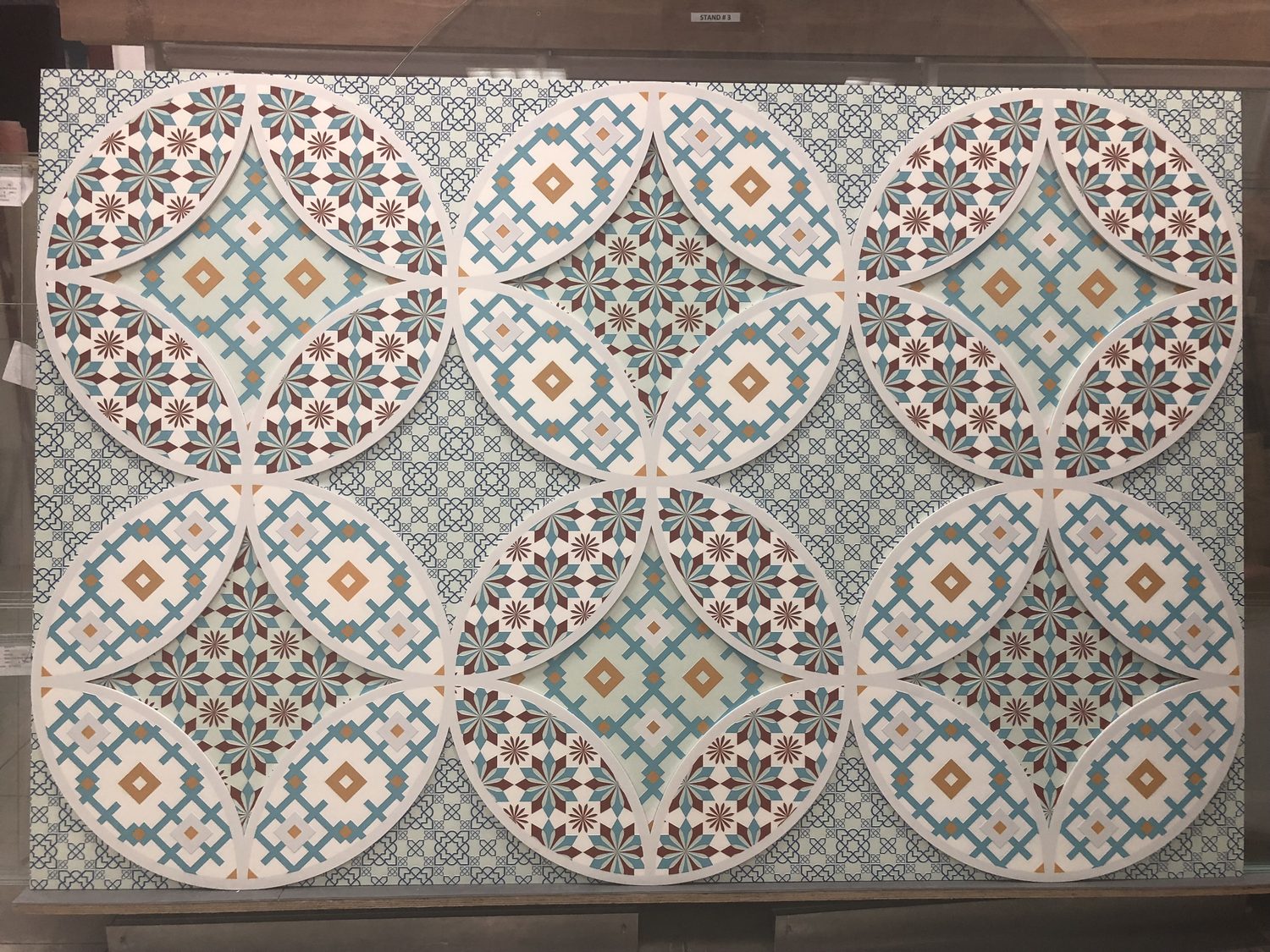 A printed acrylic panel carrying a layered Islamic geometric pattern in terracotta, blue and cream
