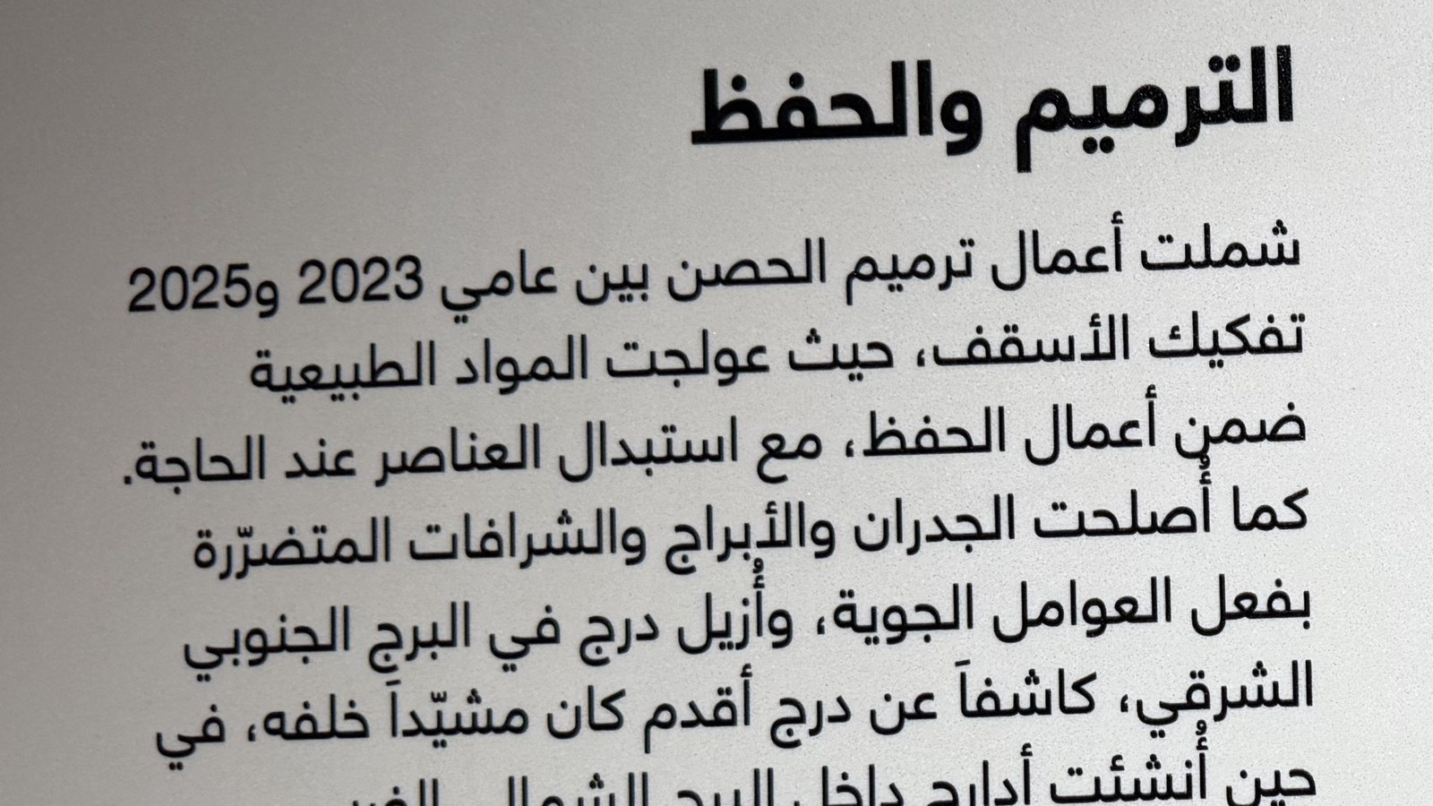 Close view of Arabic interpretation text printed directly onto a plastered wall at a heritage site in the UAE, the small type sharp against the plaster