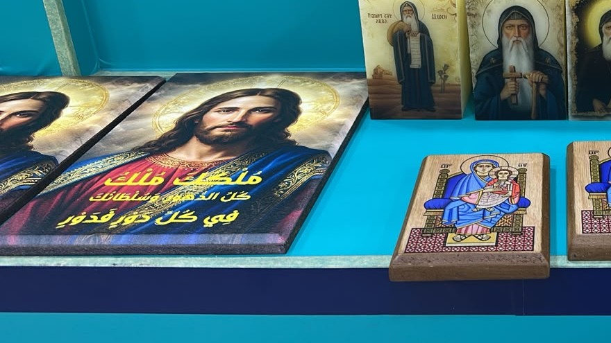 لوحان مطبوعان بصورة السيد المسيح، يحمل أحدهما آية من المزامير بالعربية، بجانب شموع مطبوعة ولوحة خشبية لأيقونة