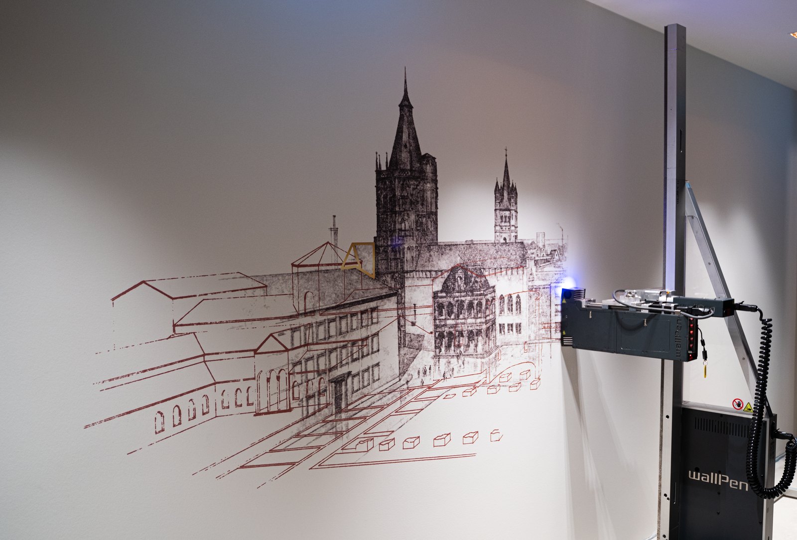 A fine architectural line drawing of a city skyline printed directly onto a wall, with the wall printer alongside it
