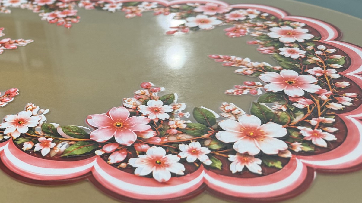 A scalloped pink and white border and raised flowers on gold acrylic, seen from an angle