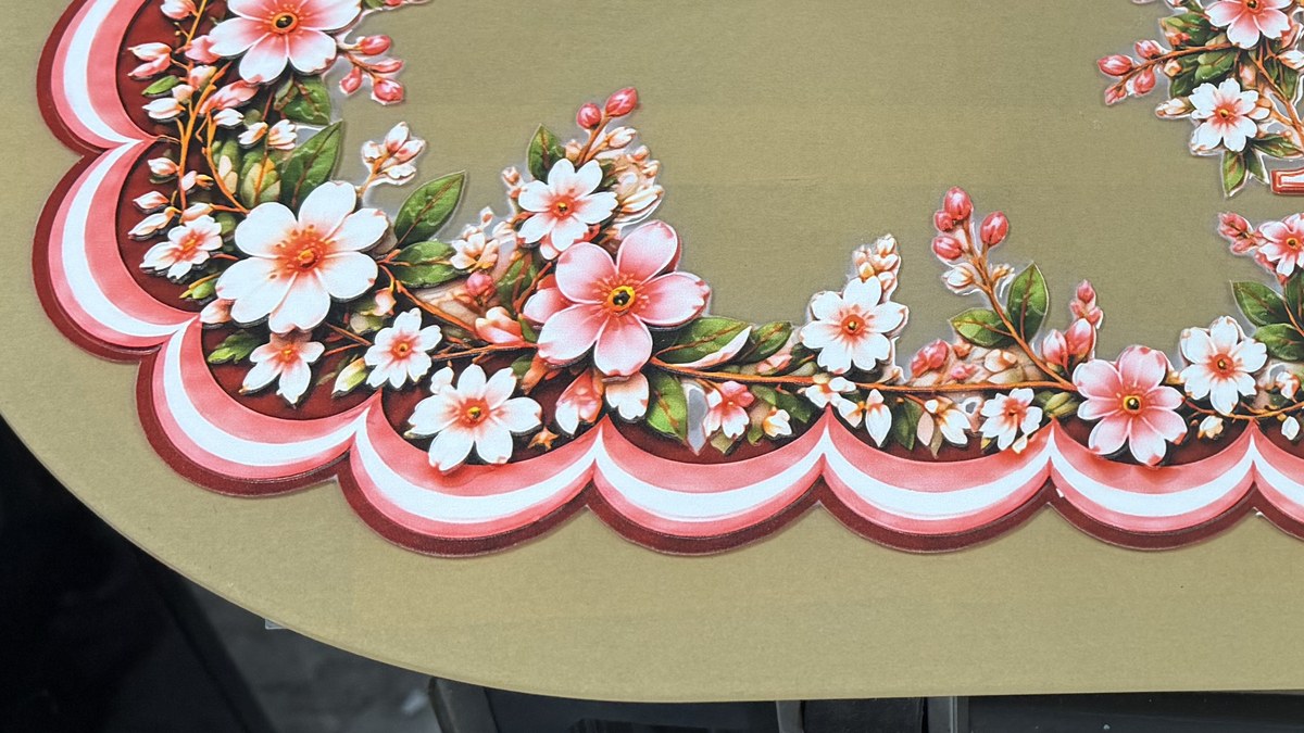Part of a printed wreath on gold acrylic: pink and white blossom, green leaves and a scalloped border in pink, white and deep red, with the bare gold sheet around it