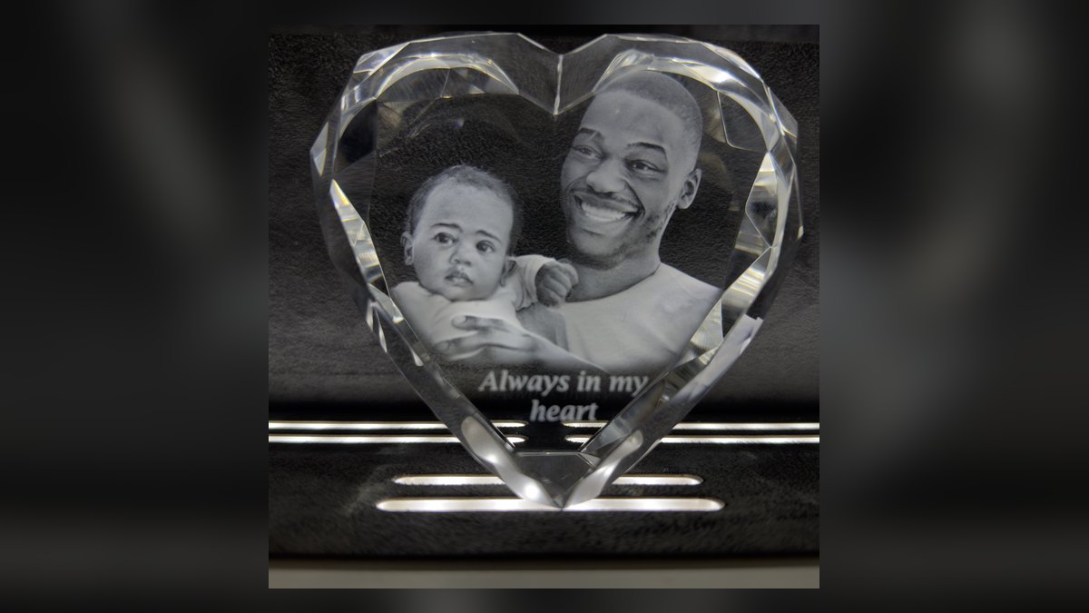 كريستالة على شكل قلب بحواف مشطوفة، محفور بداخلها أب مبتسم وطفله وعبارة Always in my heart، على منصة عرض مضيئة