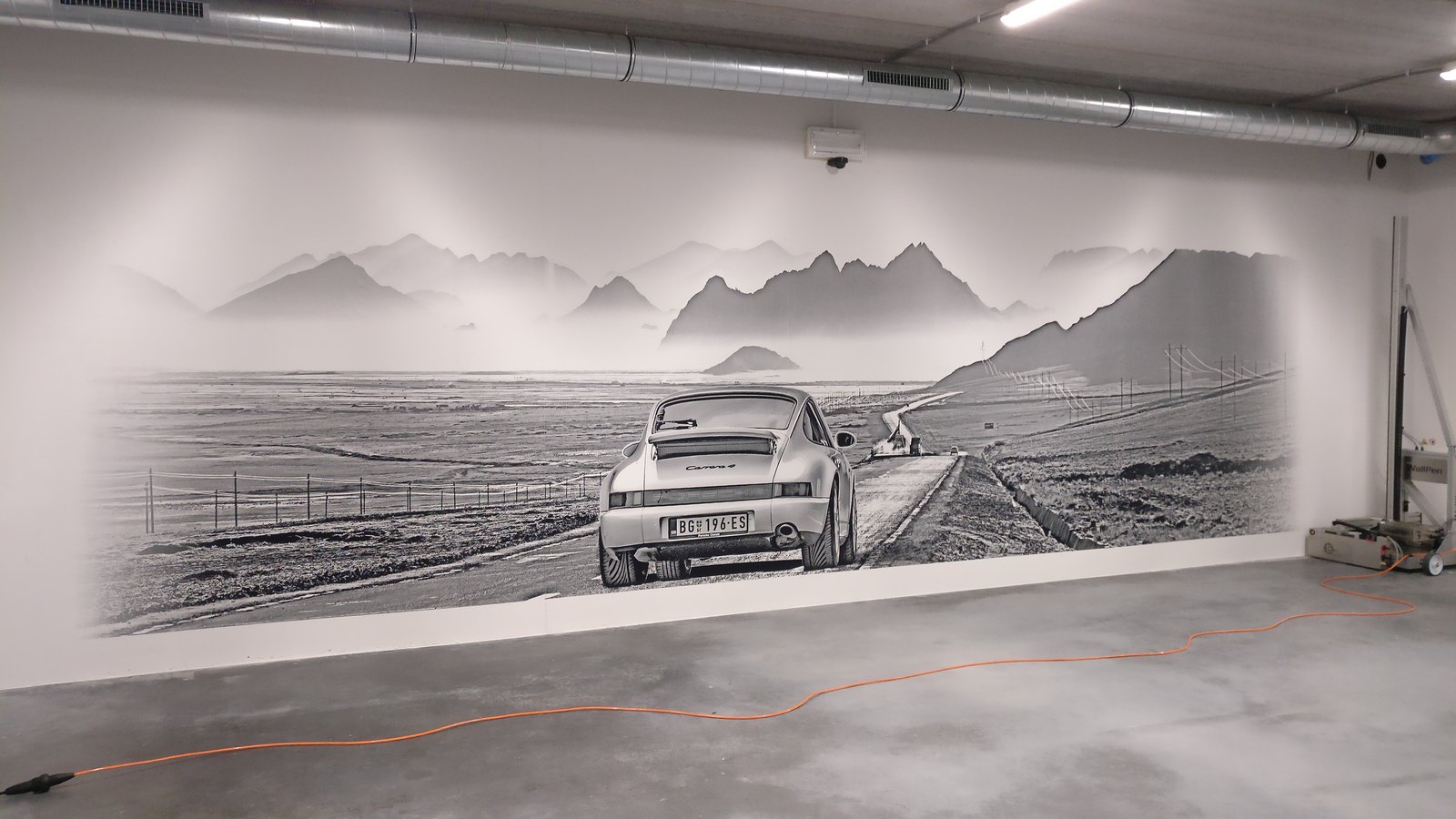 A monochrome photographic mural running the full width of an interior wall, printed directly onto the plaster