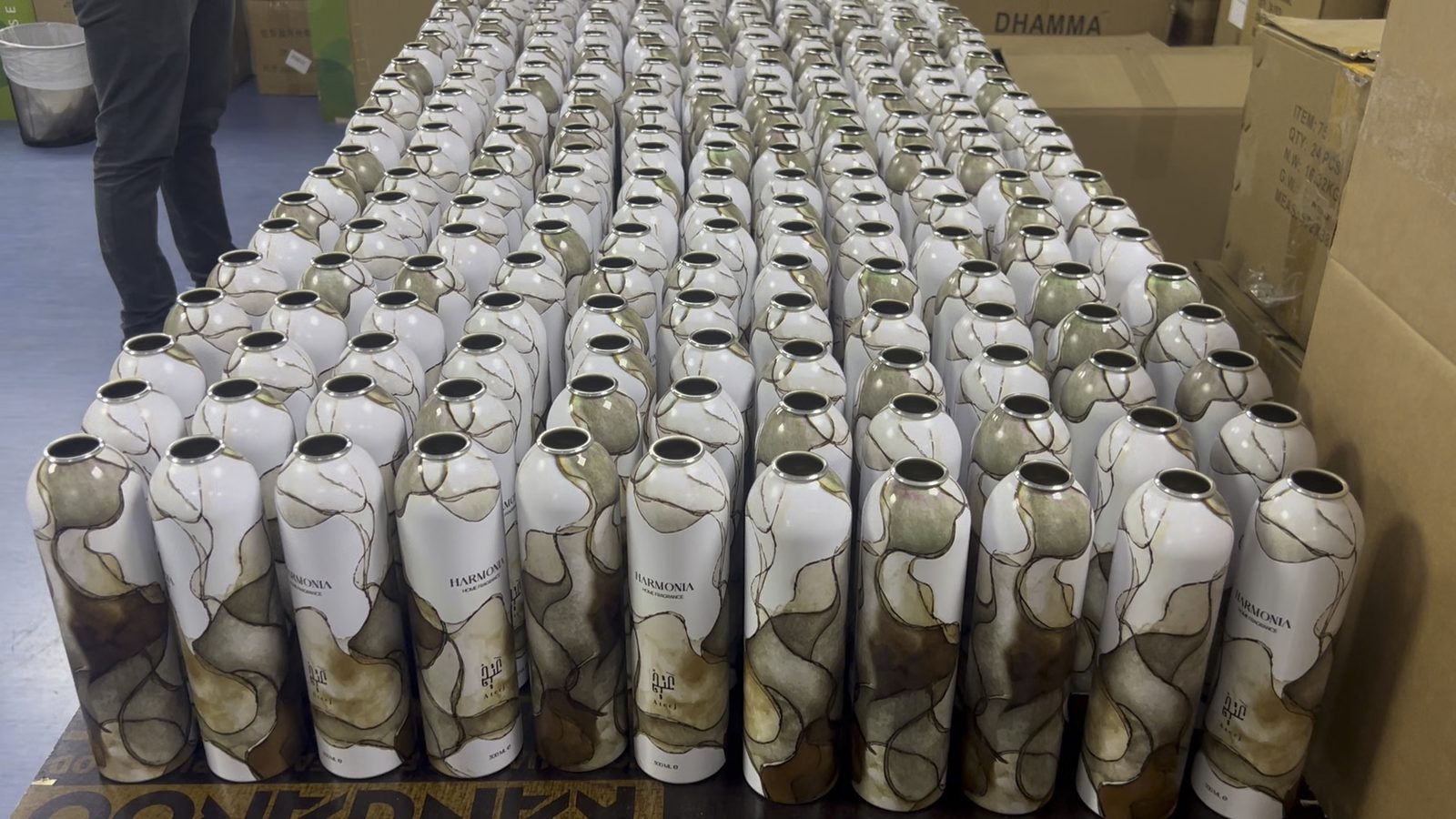A full run of aluminium body spray cans printed with a brown marble-effect wrap, laid out in rows at the studio