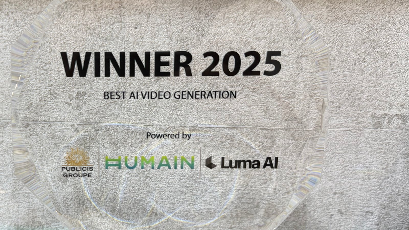 A faceted octagonal crystal award printed with black lettering reading Winner 2025 and three logos, one in a green-to-teal gradient and one in a gold colour
