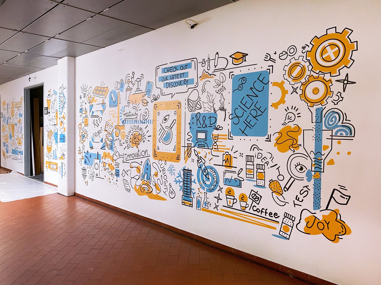 A long office corridor wall covered with an illustrated doodle mural in blue and orange around a doorway