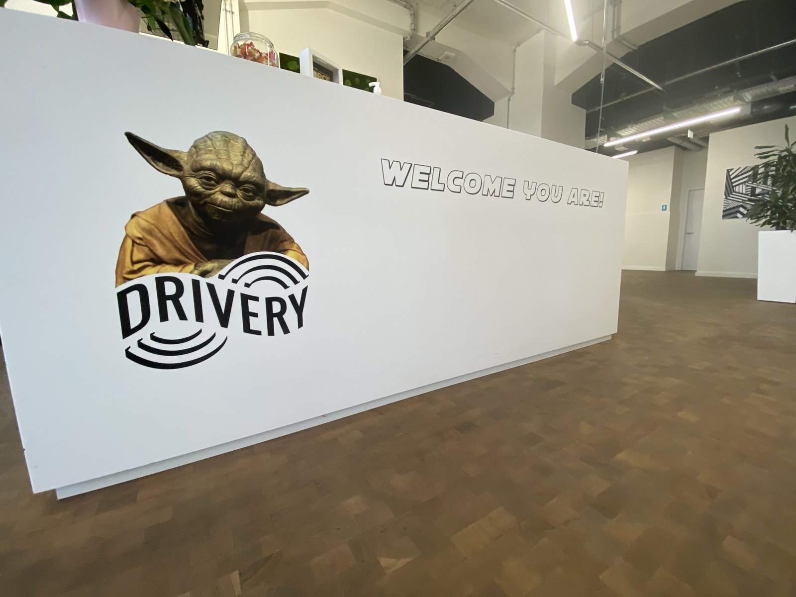 A reception desk front printed directly with a company logo and welcome lettering, in an open office