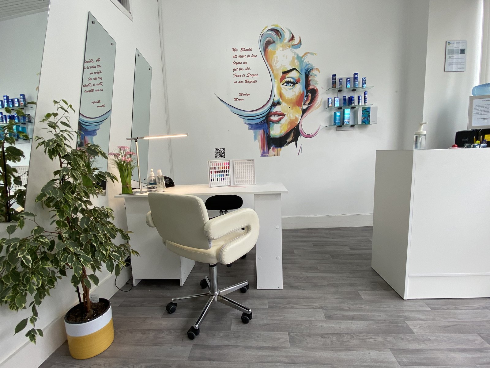 A salon interior with a colourful portrait mural on the wall behind the styling station