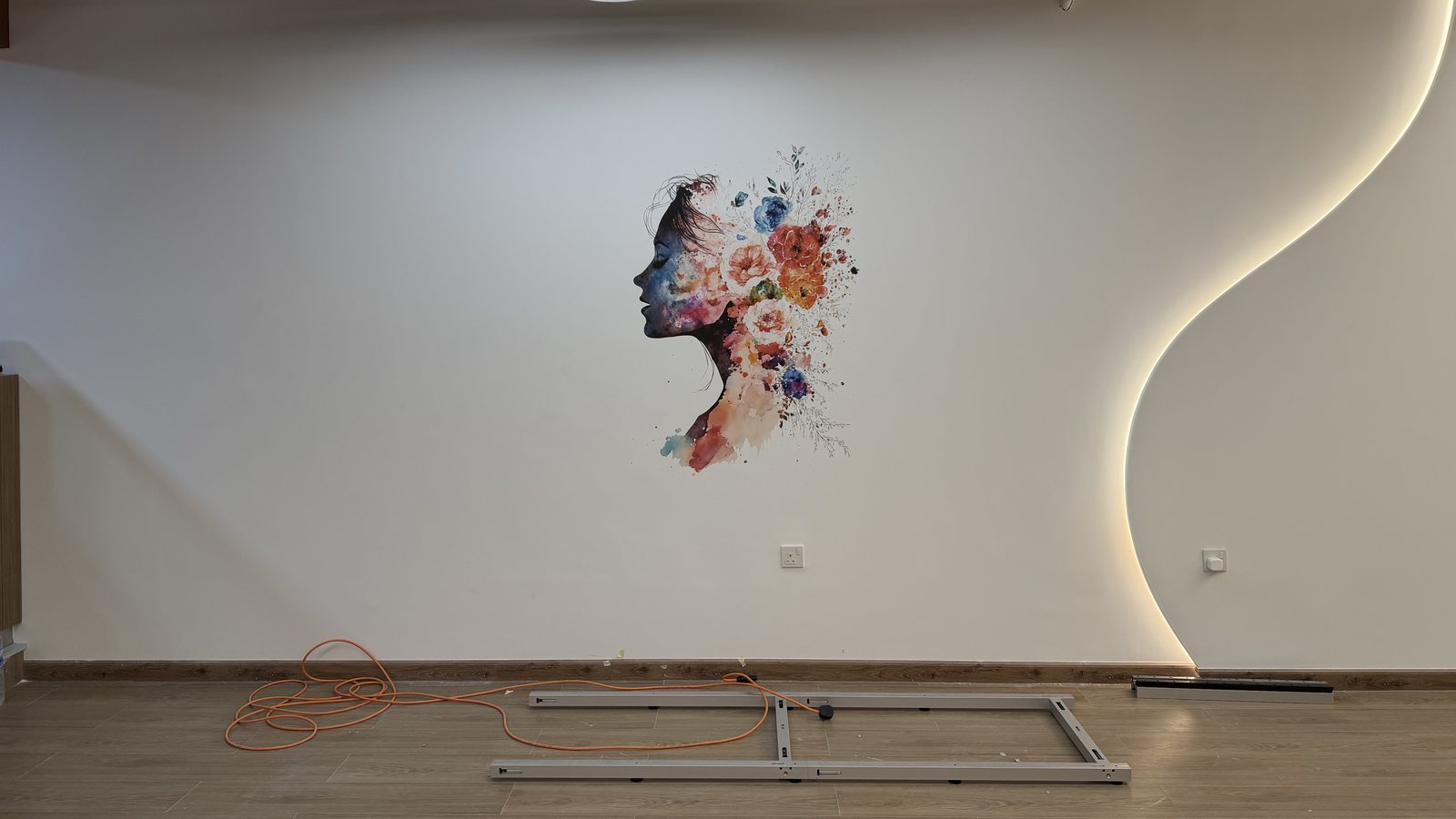 A floral portrait printed directly onto a white wall in an Abu Dhabi gym reception, with the wall printer's floor rail and power cable still laid out in front of it